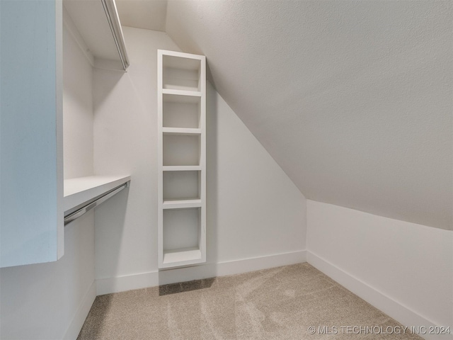 spacious closet with vaulted ceiling and carpet floors