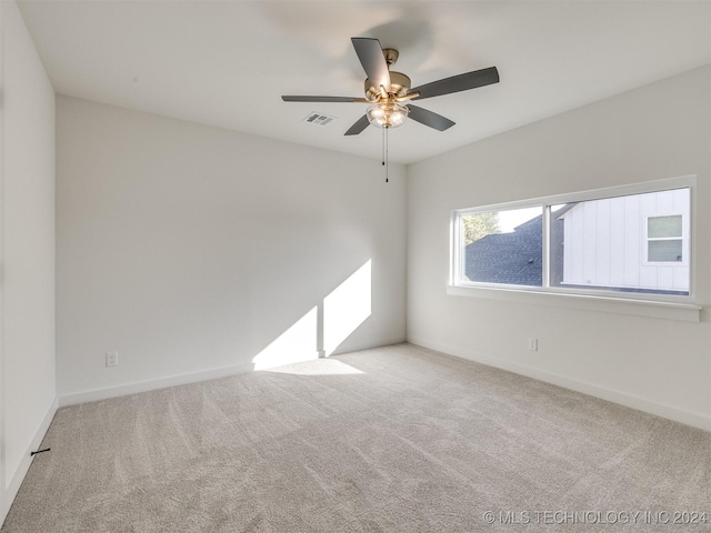 empty room featuring carpet floors, baseboards, visible vents, and ceiling fan