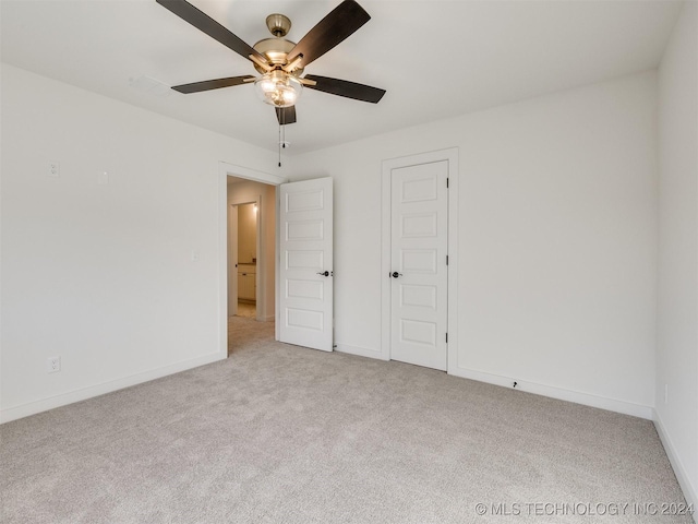 unfurnished bedroom with a ceiling fan, light carpet, and baseboards