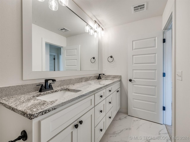 bathroom featuring marble finish floor, visible vents, a sink, and double vanity