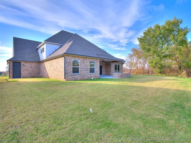 view of front facade featuring a patio area, brick siding, a front lawn, and roof with shingles