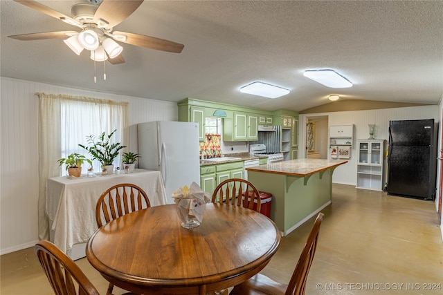 dining room with lofted ceiling, a textured ceiling, wooden walls, and ceiling fan