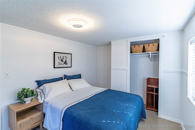 bedroom with multiple windows, a textured ceiling, and a closet