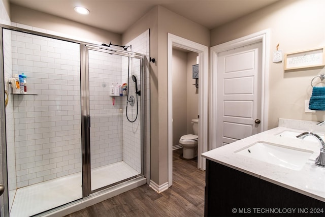 bathroom with vanity, toilet, an enclosed shower, and wood-type flooring