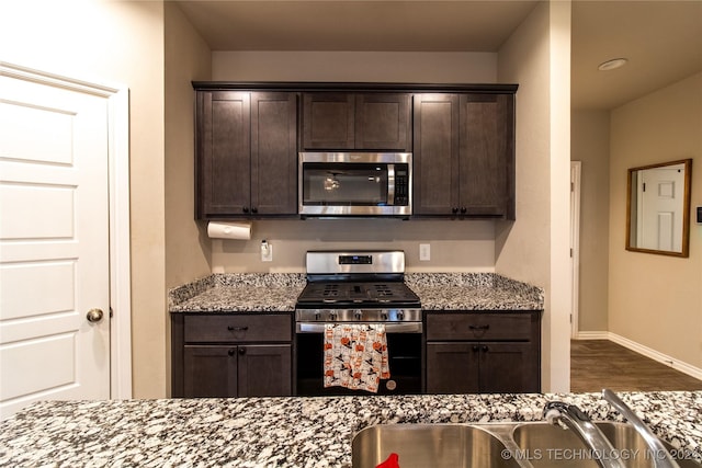 kitchen with light stone countertops, appliances with stainless steel finishes, and dark brown cabinetry