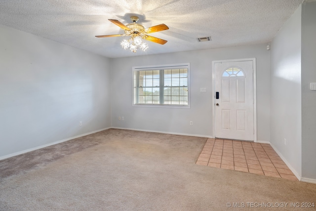 foyer with a textured ceiling, light colored carpet, and ceiling fan