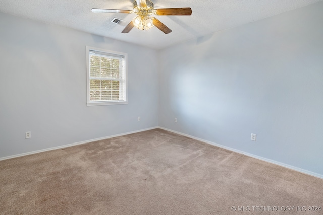 spare room featuring a textured ceiling, light colored carpet, and ceiling fan