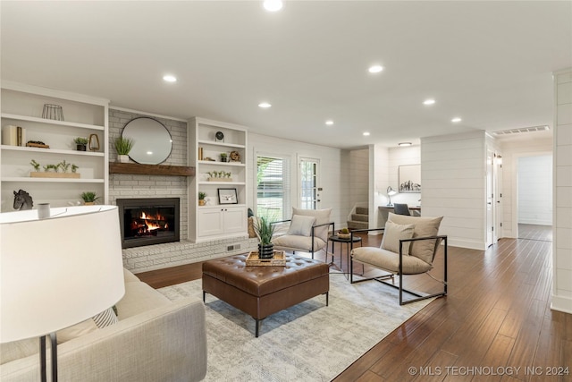 living room featuring wood walls, a fireplace, hardwood / wood-style flooring, and built in shelves