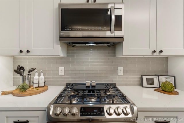 kitchen featuring decorative backsplash, light stone countertops, white cabinetry, and appliances with stainless steel finishes