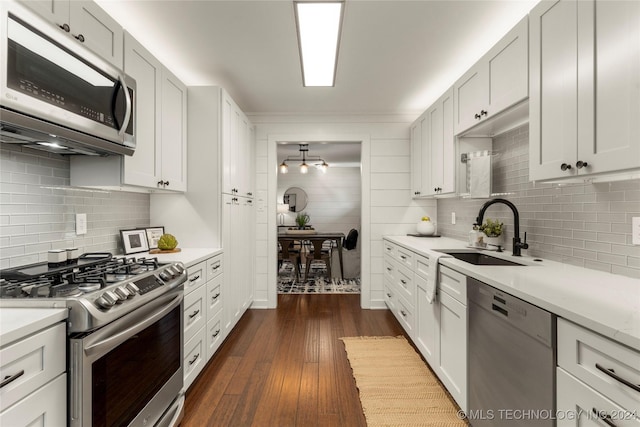 kitchen with white cabinetry, stainless steel appliances, backsplash, dark hardwood / wood-style flooring, and sink