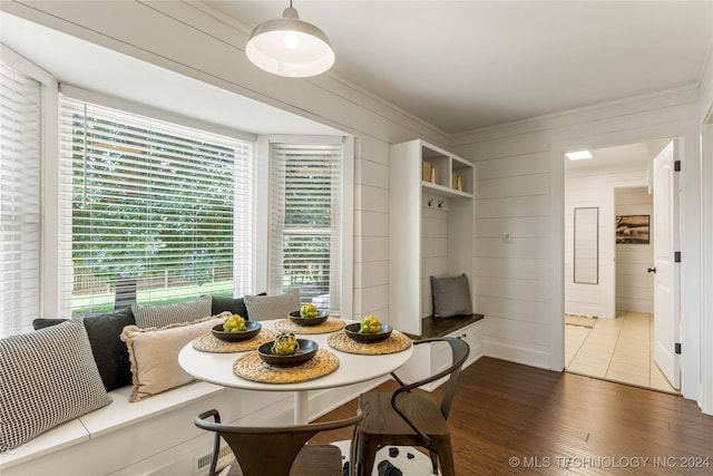 dining space with breakfast area, dark hardwood / wood-style flooring, and wood walls