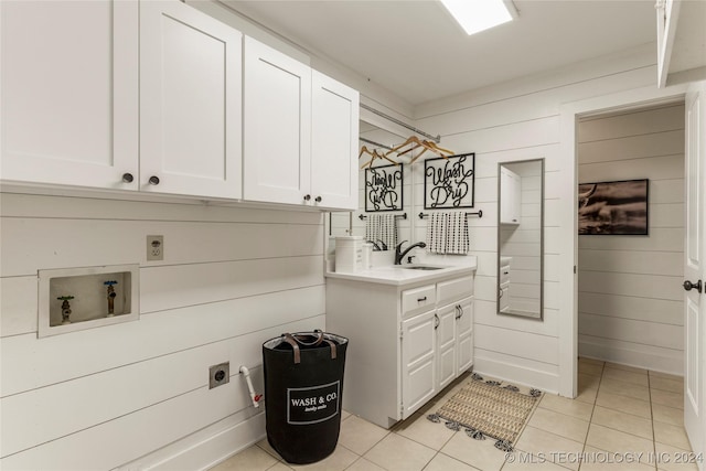 clothes washing area with light tile patterned floors, hookup for an electric dryer, washer hookup, cabinets, and sink