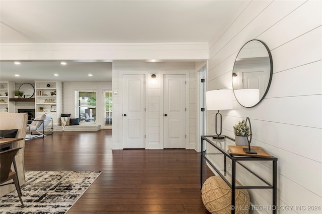 foyer entrance with wood walls, a large fireplace, and dark hardwood / wood-style floors