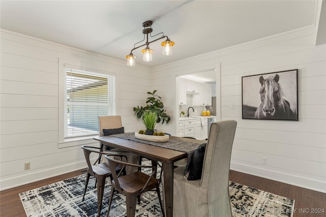 dining area featuring sink, dark hardwood / wood-style flooring, wood walls, and a notable chandelier