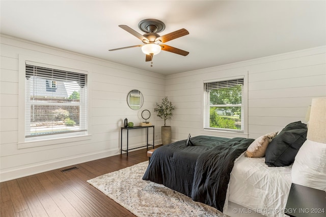 bedroom featuring ceiling fan, dark wood-type flooring, and wood walls