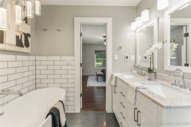 bathroom with ceiling fan, vanity, tile walls, tile patterned flooring, and a tub to relax in