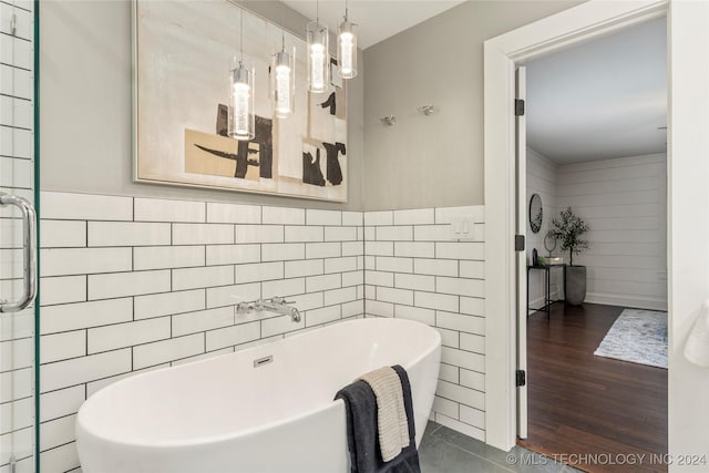 bathroom featuring hardwood / wood-style flooring, a washtub, and tile walls