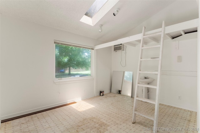 unfurnished room featuring vaulted ceiling, a textured ceiling, and a wall mounted AC