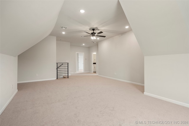 additional living space with light colored carpet, ceiling fan, and vaulted ceiling