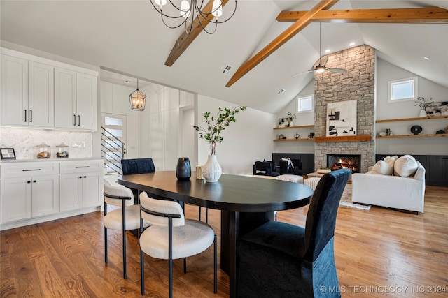 dining room featuring a fireplace, light hardwood / wood-style floors, beam ceiling, and ceiling fan with notable chandelier