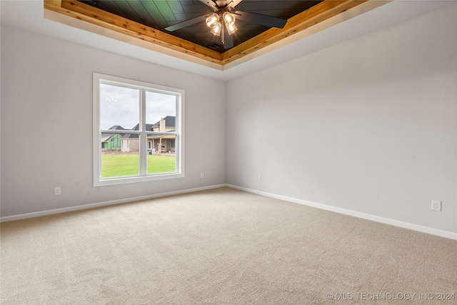 carpeted spare room with ceiling fan, a tray ceiling, and wooden ceiling