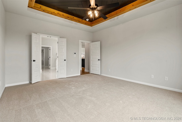 unfurnished bedroom featuring wood ceiling, carpet floors, and a raised ceiling