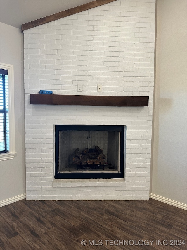 room details featuring beam ceiling, hardwood / wood-style flooring, and a brick fireplace