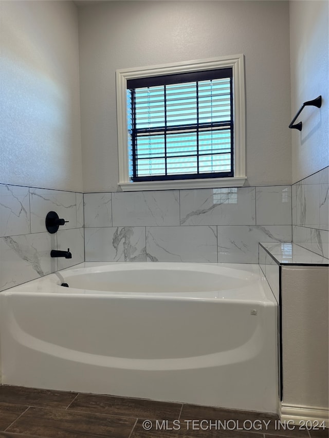 bathroom with tile walls, hardwood / wood-style flooring, and a washtub