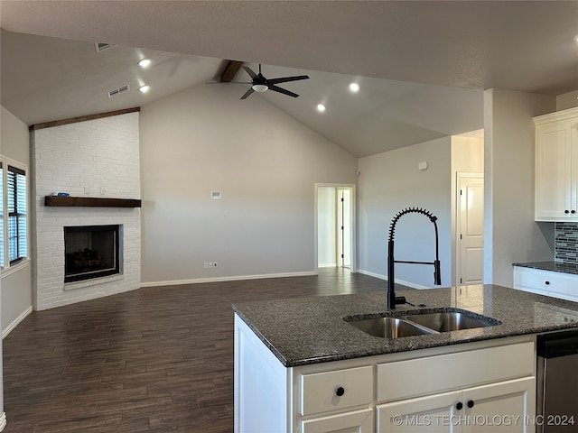 kitchen with vaulted ceiling with beams, dark stone counters, sink, white cabinets, and dark hardwood / wood-style flooring