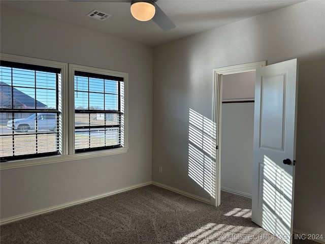 unfurnished bedroom featuring a closet, ceiling fan, multiple windows, and dark carpet