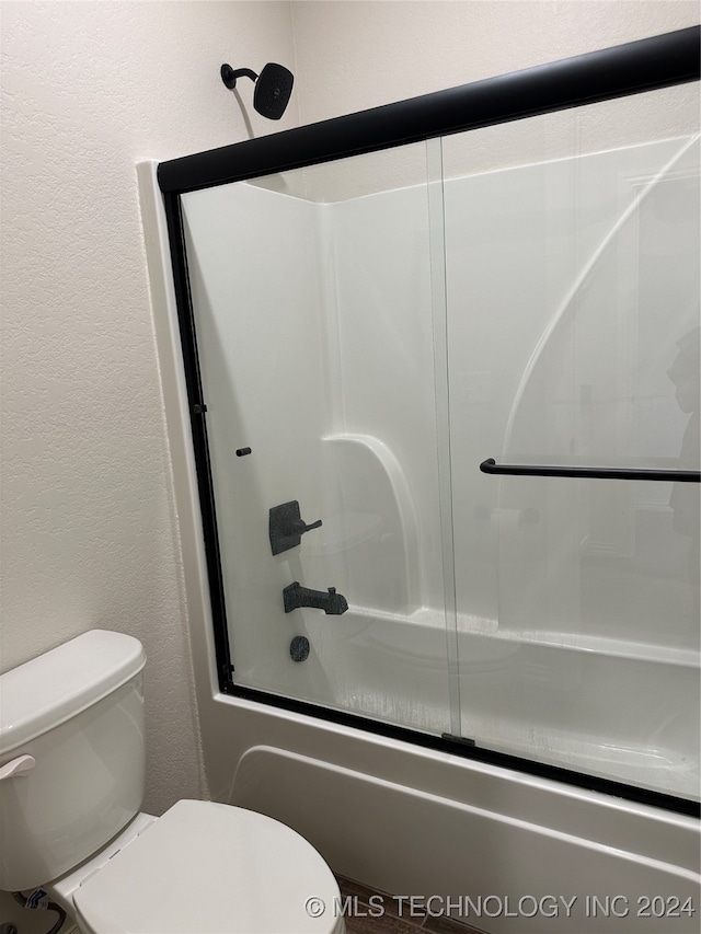 bathroom featuring bath / shower combo with glass door and toilet