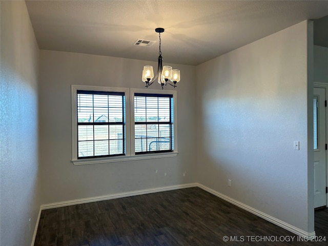 empty room featuring dark hardwood / wood-style flooring and a chandelier