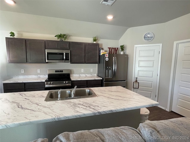 kitchen featuring sink, vaulted ceiling, a kitchen island with sink, dark brown cabinets, and appliances with stainless steel finishes