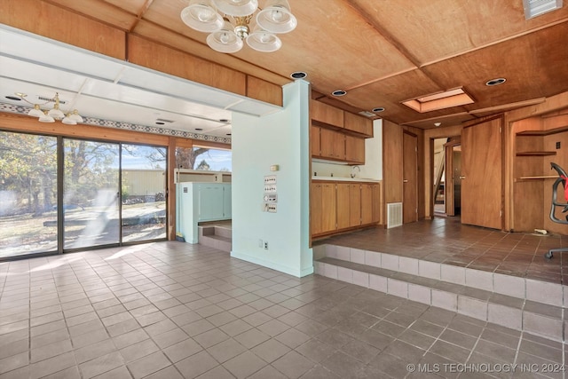 interior space with dark tile patterned flooring, wood walls, wooden ceiling, and a skylight