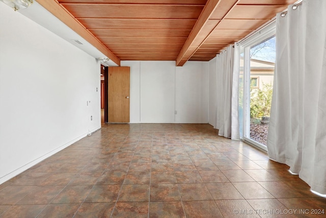 tiled empty room featuring wood ceiling and beam ceiling