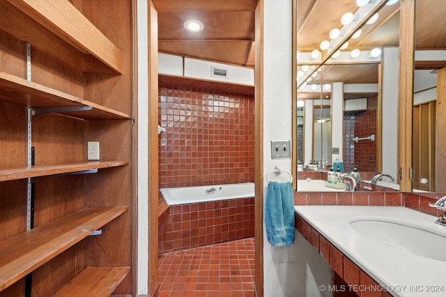 bathroom featuring vanity, tile patterned flooring, and tiled bath