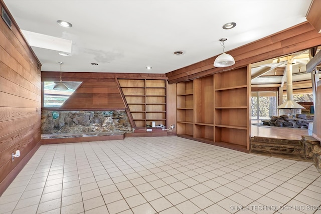 unfurnished living room featuring light tile patterned floors and wooden walls