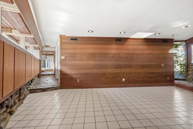 interior space with a healthy amount of sunlight, a skylight, and wooden walls