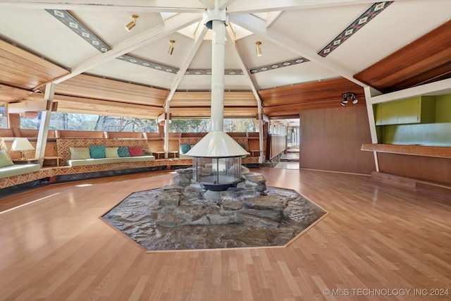 interior space featuring beam ceiling, wooden walls, and hardwood / wood-style flooring