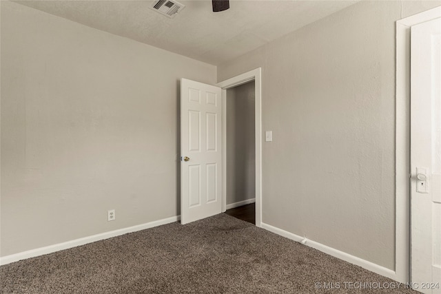 spare room with dark colored carpet and ceiling fan