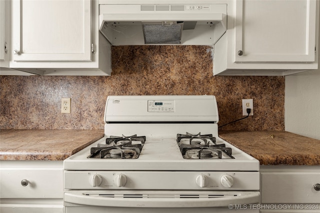 kitchen featuring white gas stove, decorative backsplash, and white cabinets