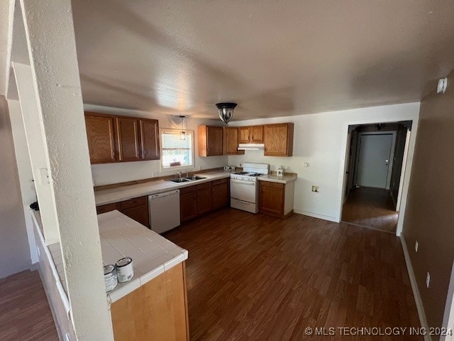 kitchen with tile counters, sink, dark hardwood / wood-style floors, and white appliances