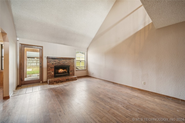 unfurnished living room featuring hardwood / wood-style flooring, lofted ceiling, and plenty of natural light