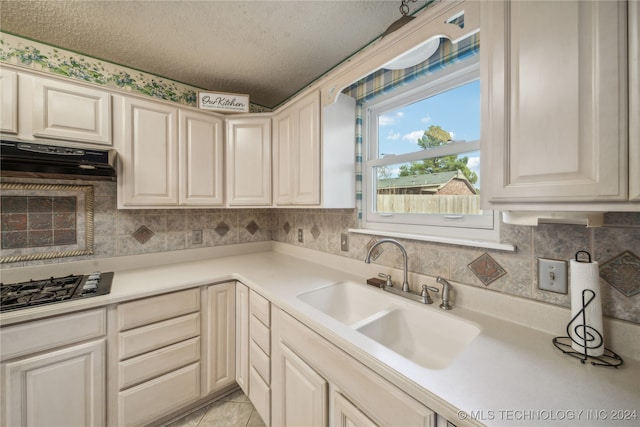 kitchen with oven, light tile patterned flooring, sink, a textured ceiling, and gas stovetop