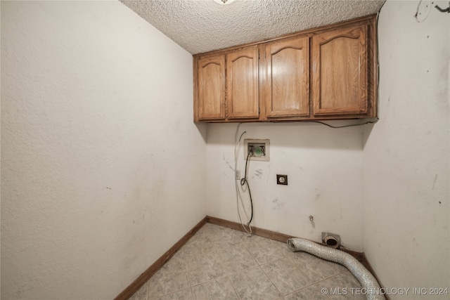 clothes washing area with hookup for an electric dryer, a textured ceiling, hookup for a gas dryer, washer hookup, and cabinets