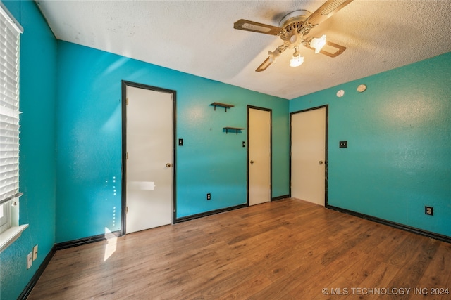 unfurnished bedroom with a textured ceiling, hardwood / wood-style flooring, and ceiling fan