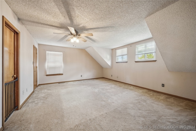 bonus room featuring lofted ceiling, a textured ceiling, light colored carpet, and ceiling fan