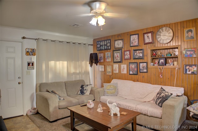 living room featuring ceiling fan and wood walls