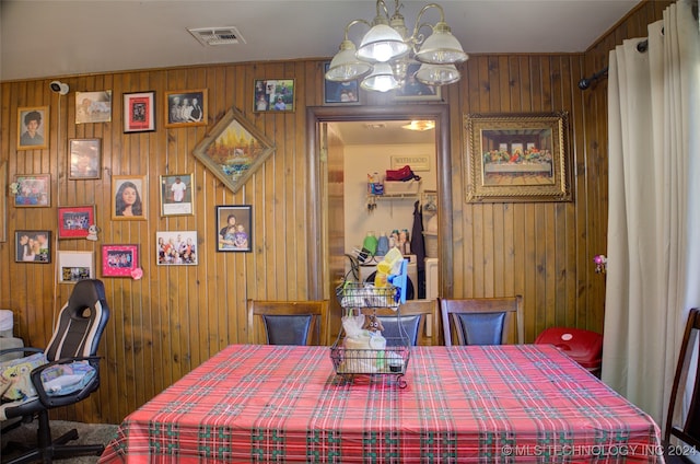 dining space featuring wood walls and a chandelier