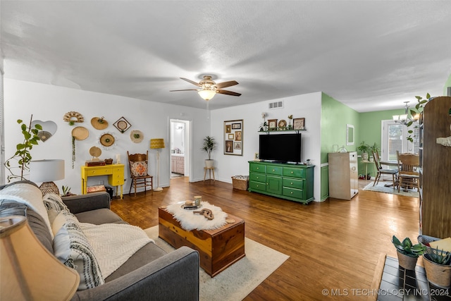 living room with a textured ceiling, hardwood / wood-style flooring, and ceiling fan with notable chandelier